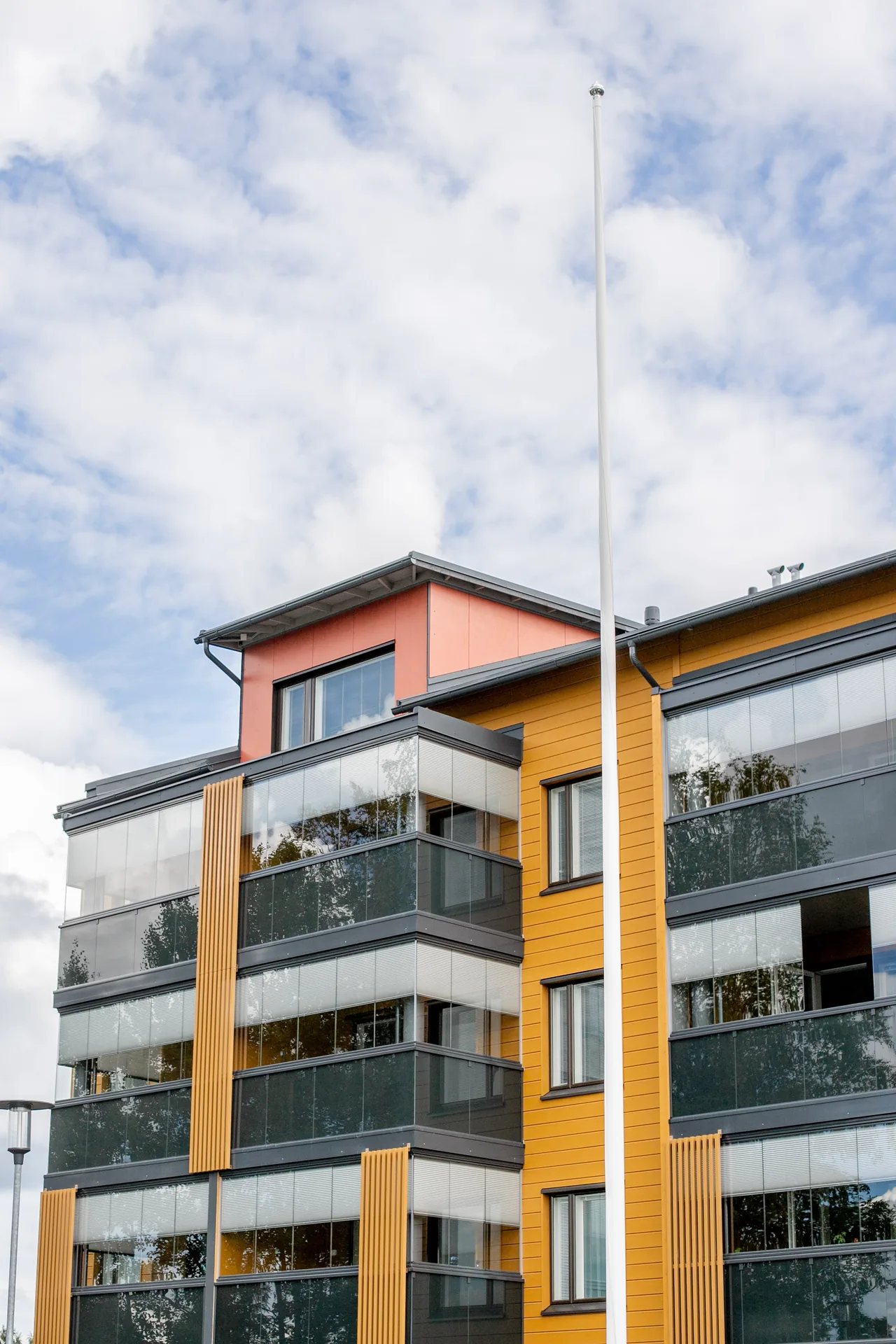 Vaaleat parvekekaihtimet peittävät osan keltaisen kerrostalon parvekelasituksista.