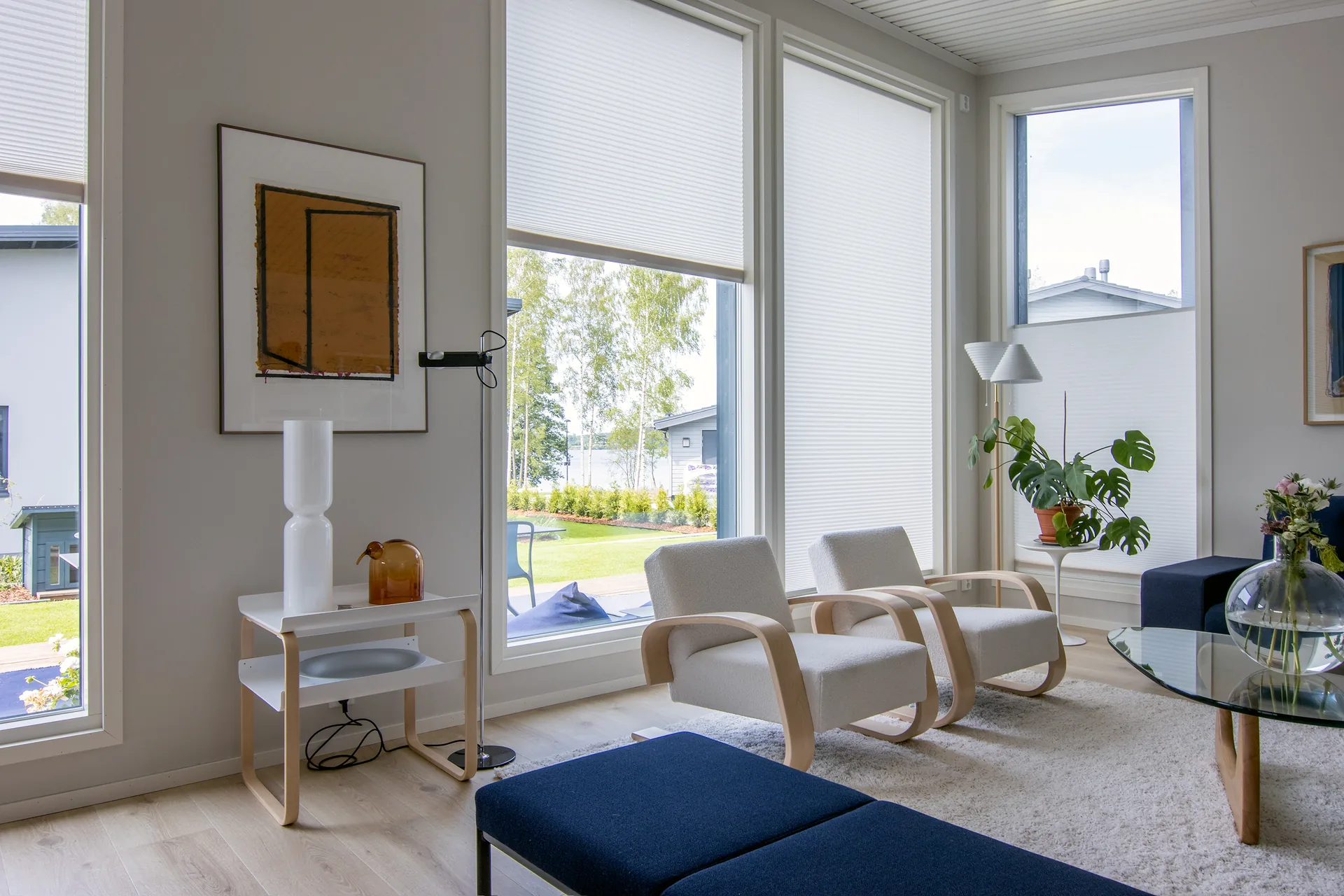 Valkoiset Visor-kaihtimet peittävät olohuoneen korkeita ikkunoita eri korkeuksilta.