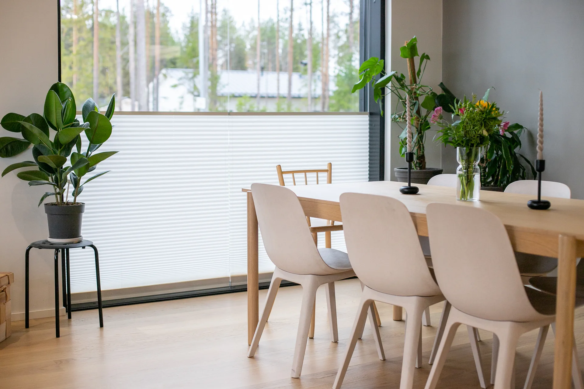 Valkoiset ikkunakaihtimet peittävät osan ikkunasta kalustetussa ruokailutilassa.